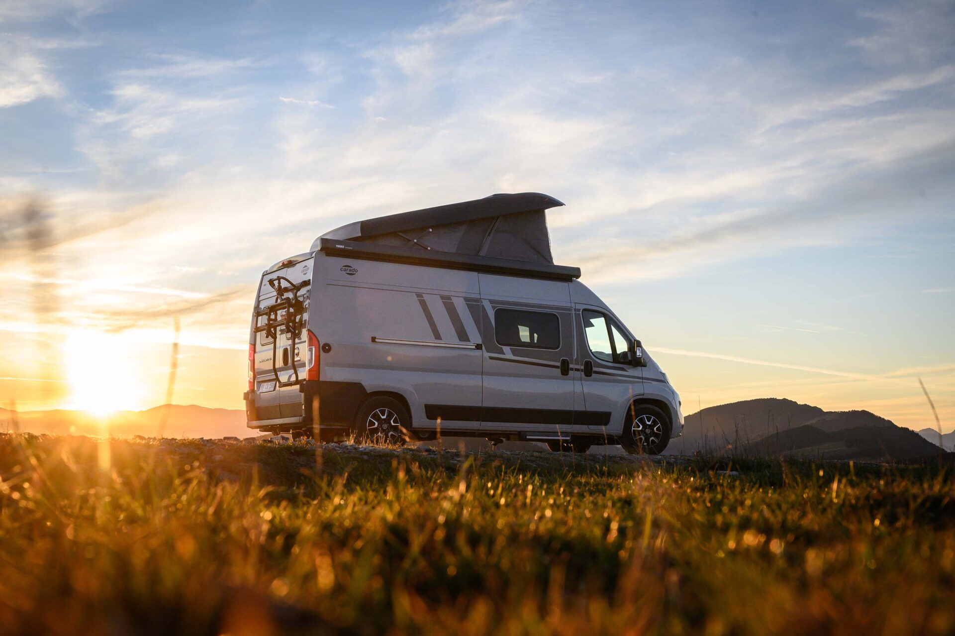 Camper auf einer Wiese vor dem Sonnenuntergang